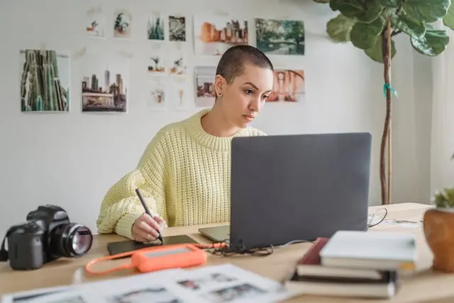 mujer frente a laptop con camara fotografica